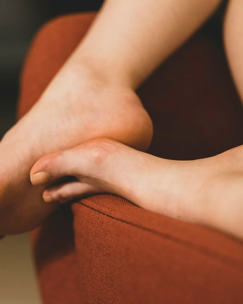 Pieds nus au repos sur un fauteuil terracotta, lumière chaude
